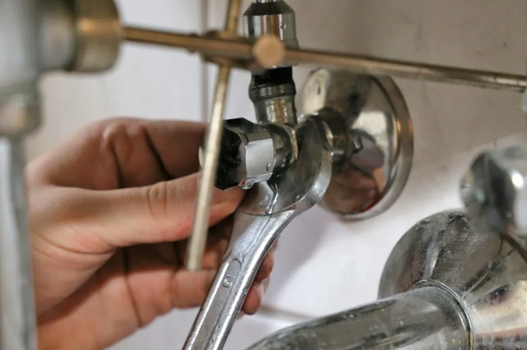 Wrench on a chrome shut-off valve under a sink