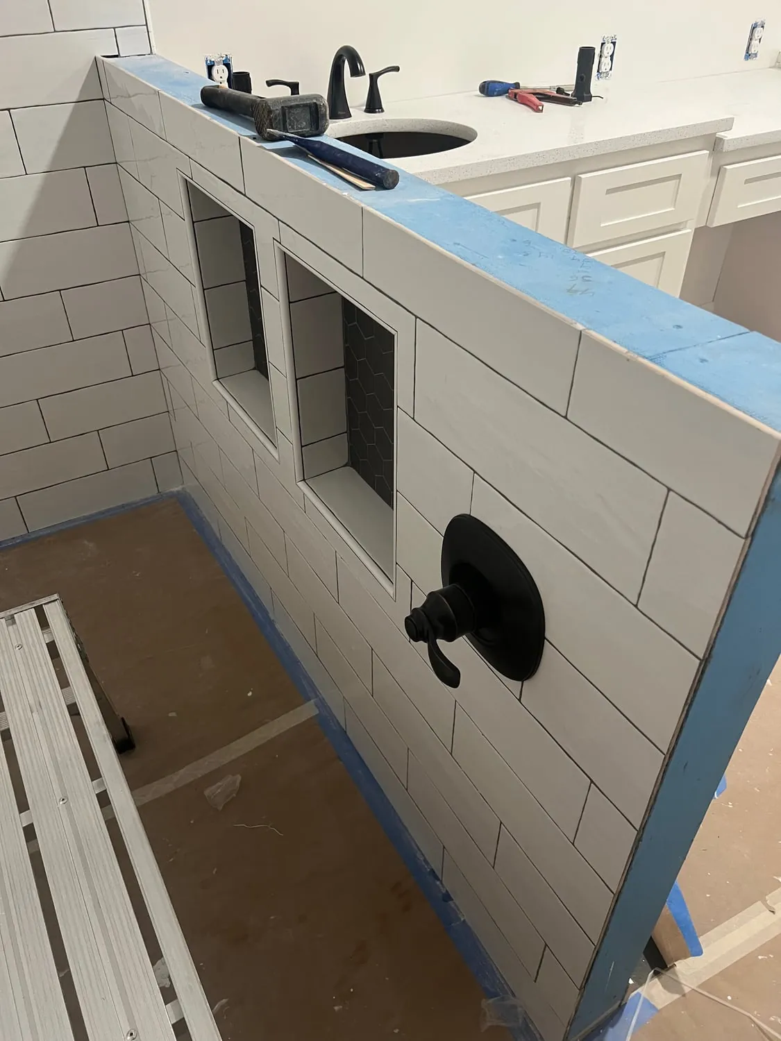 Shower valve on a newly tiled pony wall with two niches during a bathroom remodel