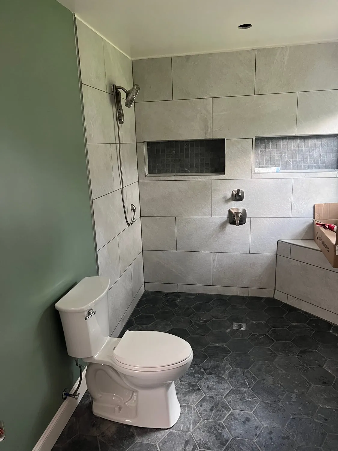 Remodeled bathroom with a new toilet, a walk-in shower and a hex tile floor