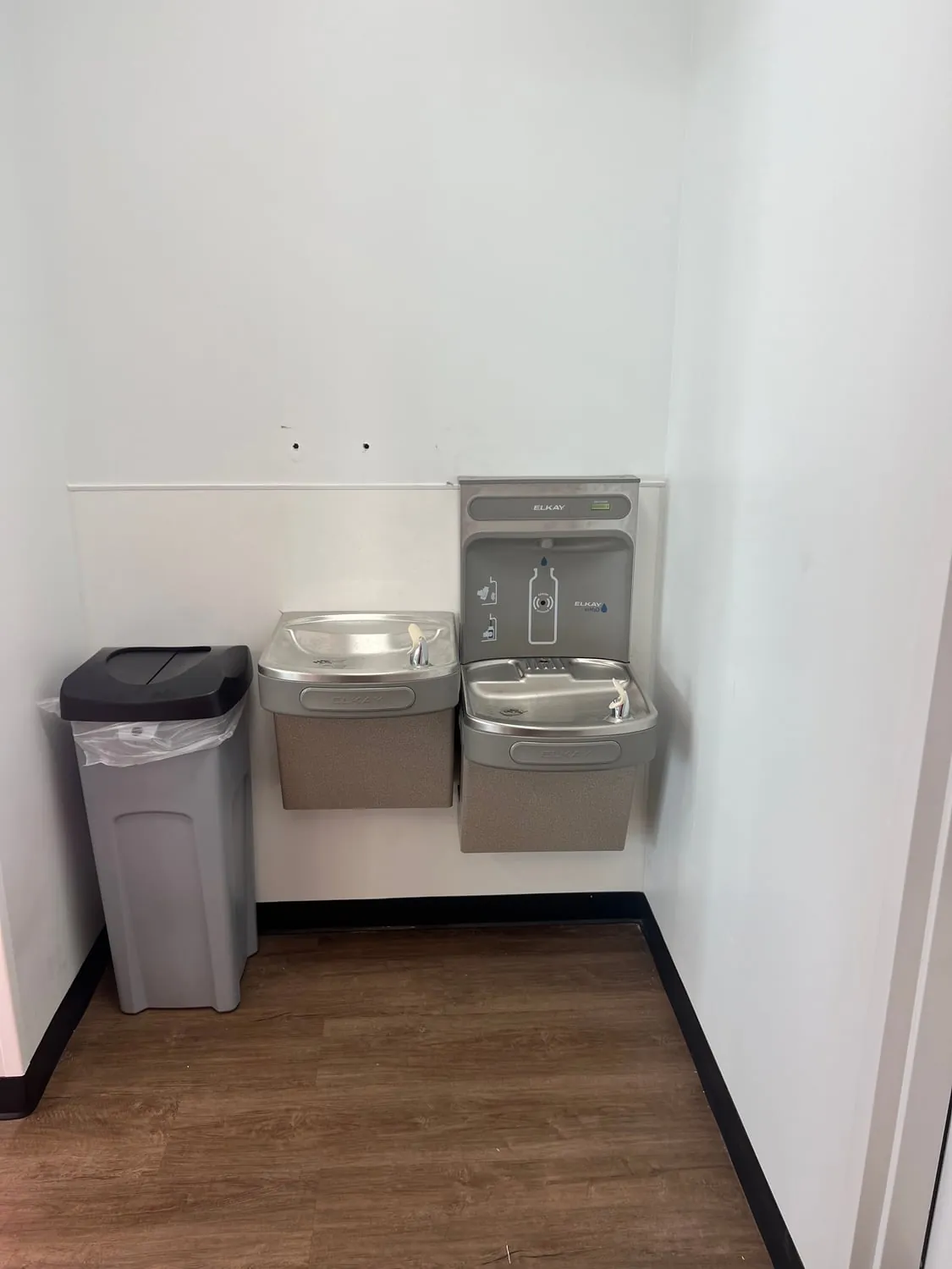Bottle filler and two-level drinking fountain mounted on a white wall
