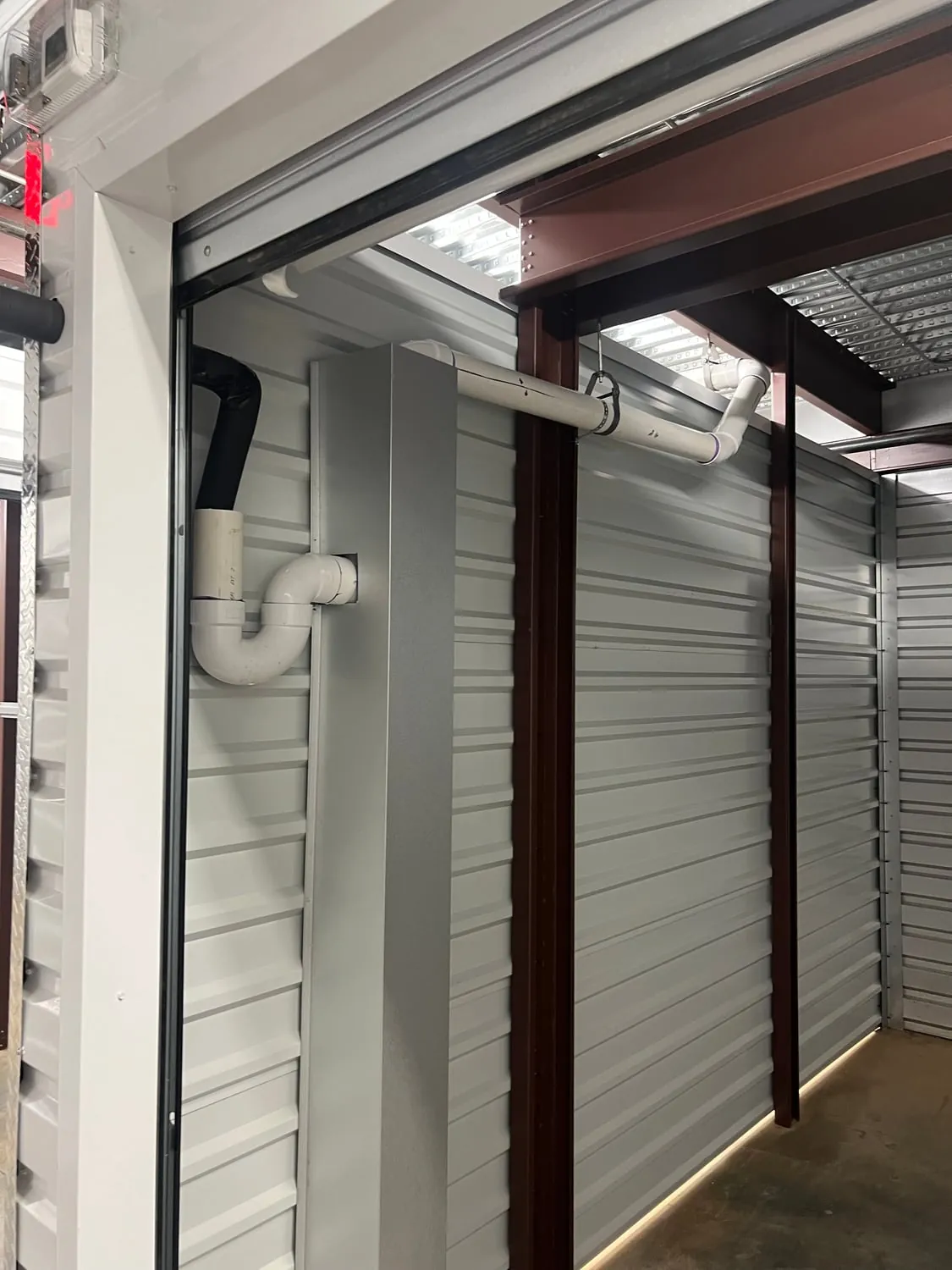 PVC drain piping and trap run along the wall of a storage building unit