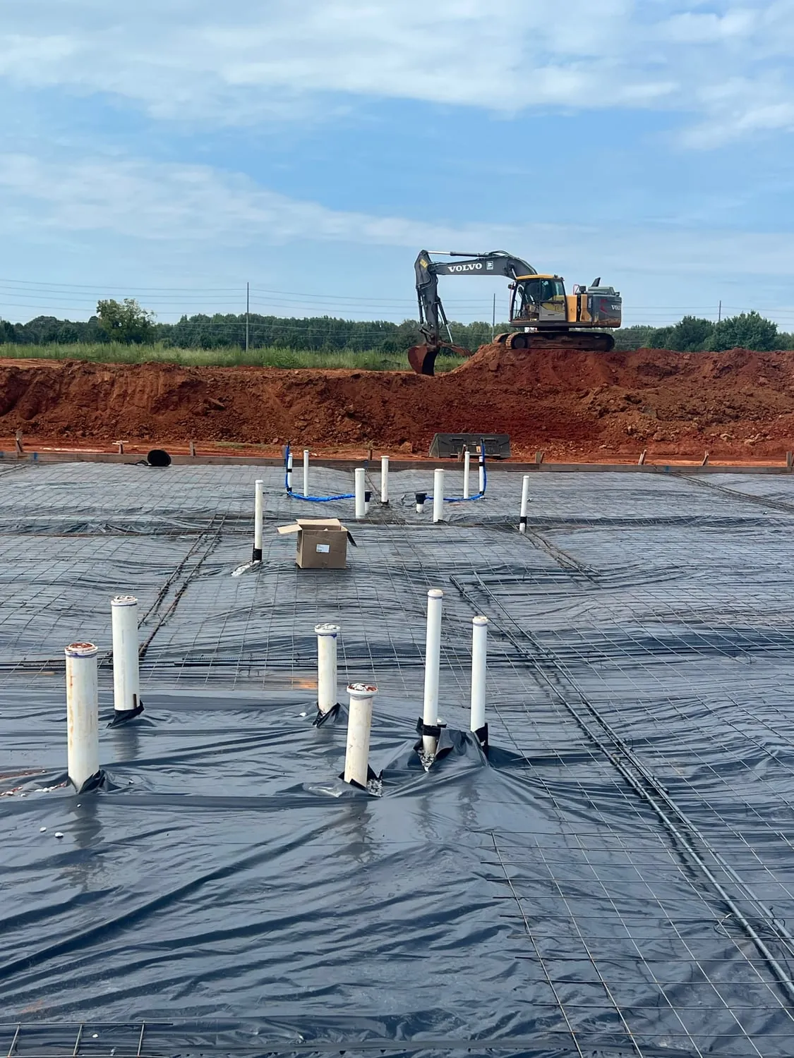 Plumbing stubbed up through a vapor barrier on a commercial slab before the pour