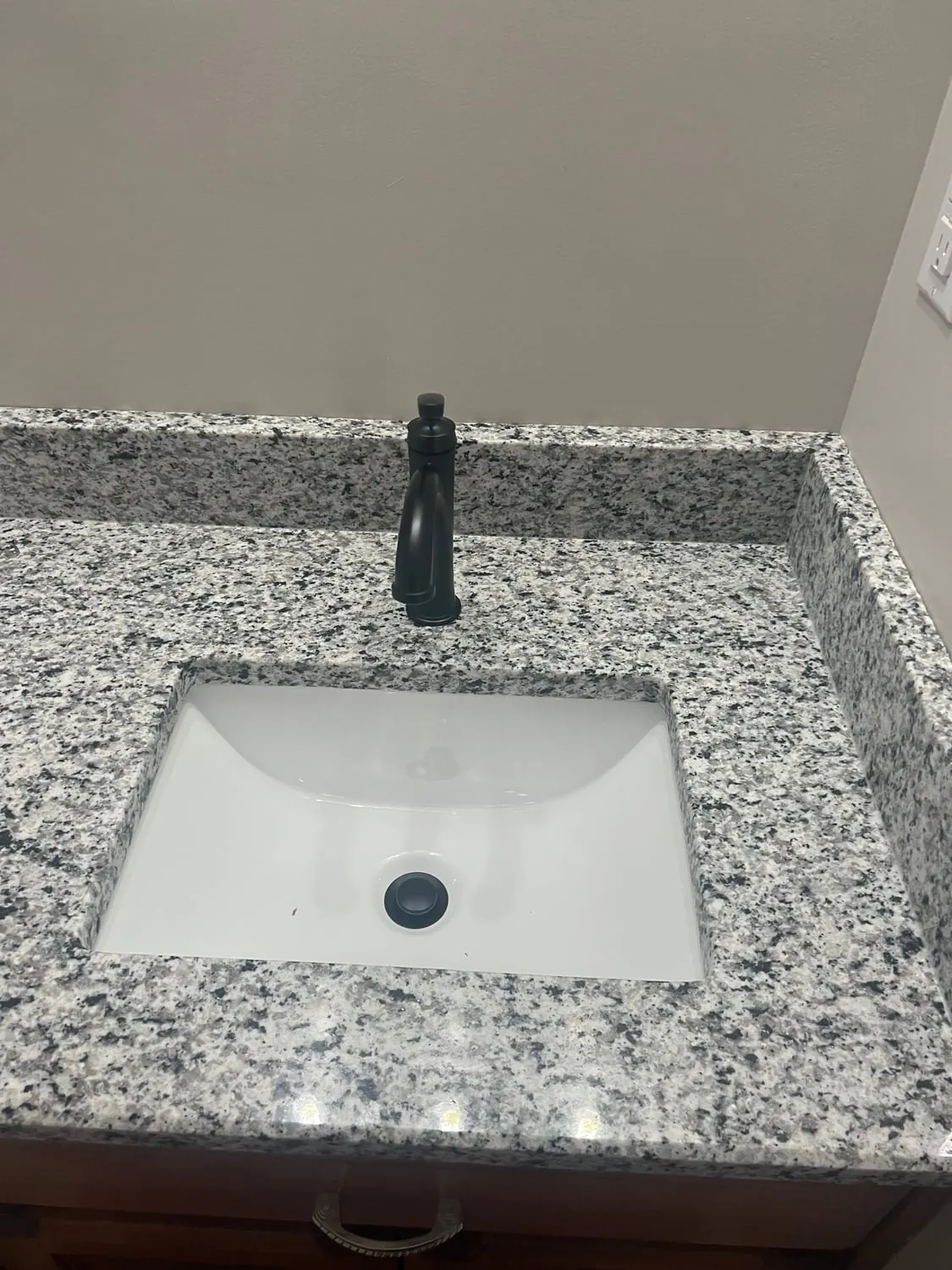Matte black faucet on a granite vanity top with an undermount sink