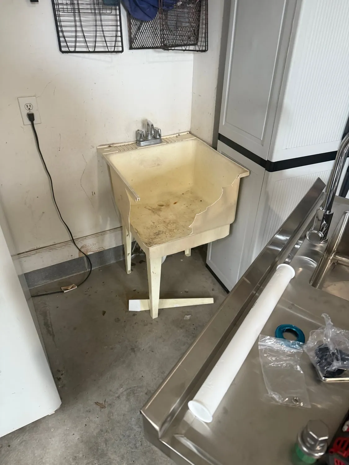 Old laundry sink with its replacement stainless sink on the floor beside it
