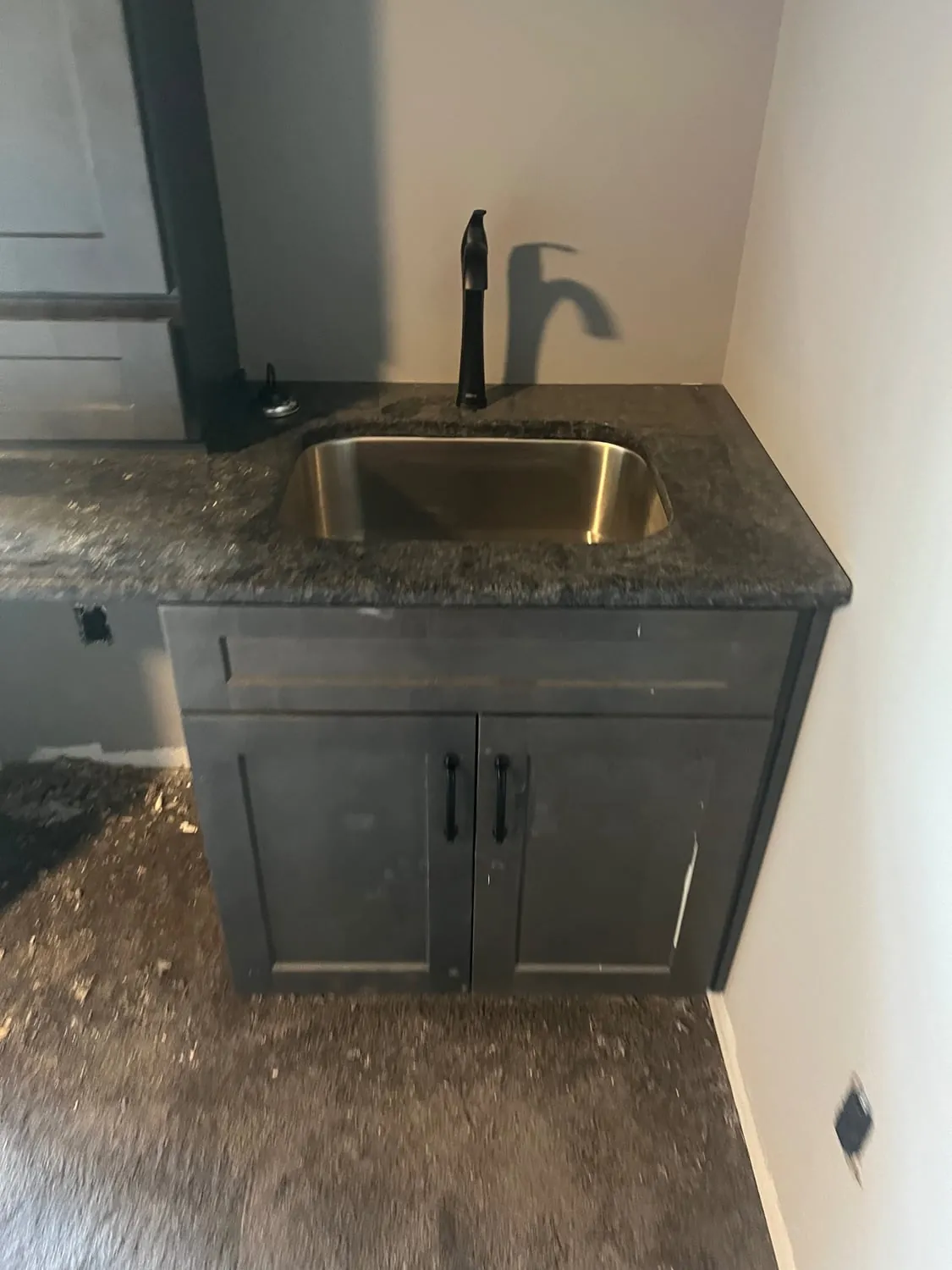 Stainless sink and black faucet on a dark vanity cabinet