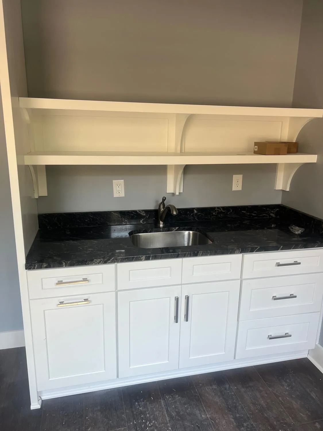 Stainless sink and faucet in a white cabinet run with a black granite top